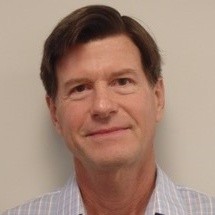 Close-up photo of Tom Conover, light background and smiling.